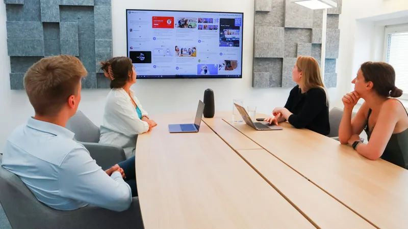 Team meeting around a conference table in front of a screen