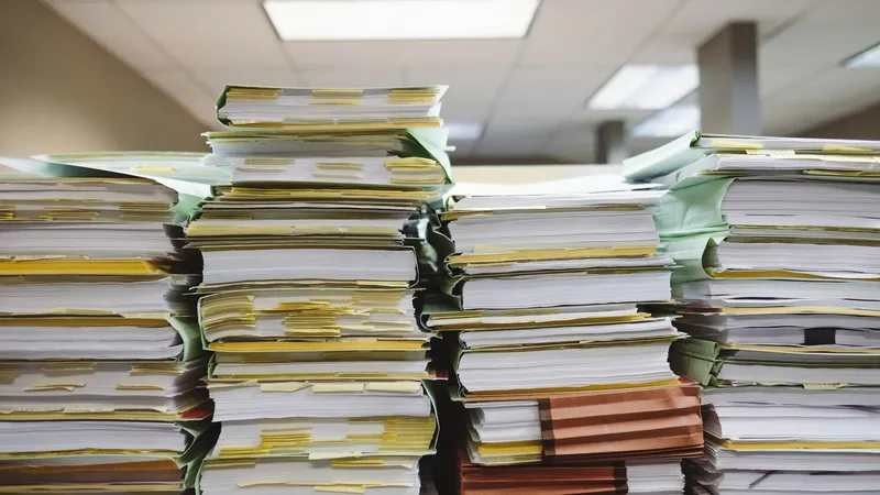 Tall stacks of paper documents and file folders in an office